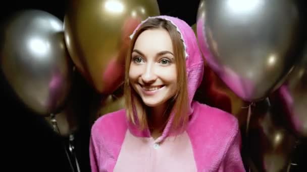 Dziewczyna w różowej piżamie kigurumi z balonami. piżama party — Wideo stockowe