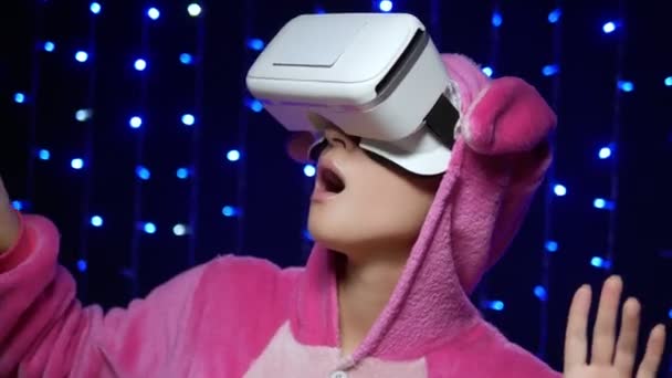 Mädchen in rosa Pyjama kigurumi in vr Brille auf schwarzem Hintergrund. Pyjama-Party — Stockvideo