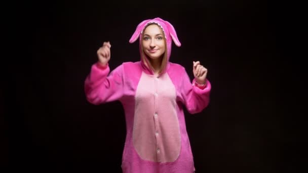 Niña en pijama kigurumi rosa en gafas VR sobre fondo negro. fiesta de pijama — Vídeo de stock