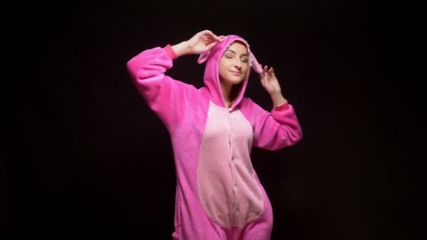 Meisje in roze pyjama kigurumi in Vr bril op een zwarte achtergrond. pyjamafeest — Stockvideo