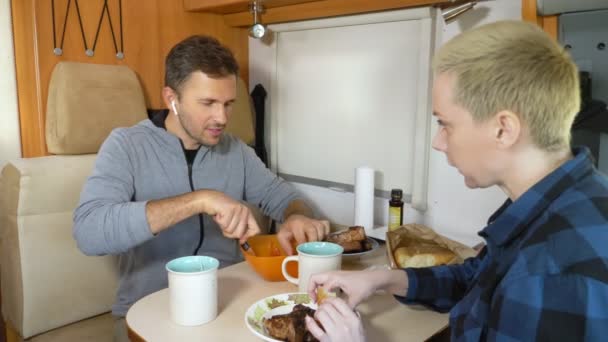 Hombre y mujer comen la carne en la mesa en la autocaravana — Vídeos de Stock