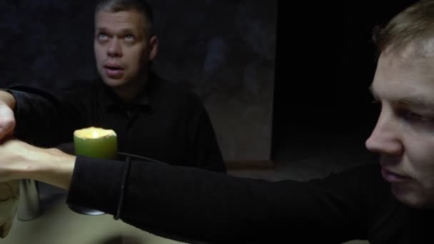 Сеанс спіритизму групи людей, що сидять за круглим столом, тримаючи руки — стокове відео