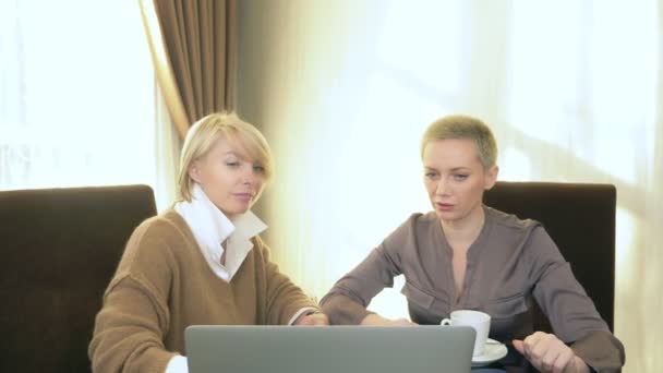 Twee vrouwen praten terwijl ze in een kantoor voor een laptop zitten — Stockvideo