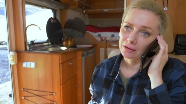 Vrouw gebruikt een mobiele telefoon terwijl zitten aan een tafel in een camper — Stockvideo