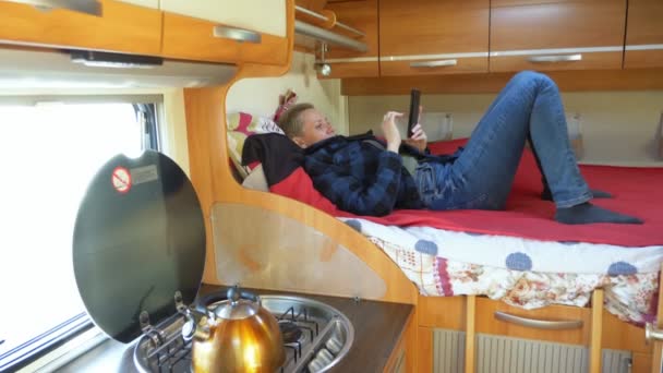 Женщина использует мобильный телефон, лежащий на кровати в доме на колесах — стоковое видео