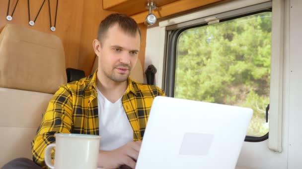 Man met behulp van zijn laptop zitten aan een tafel in de camper — Stockvideo