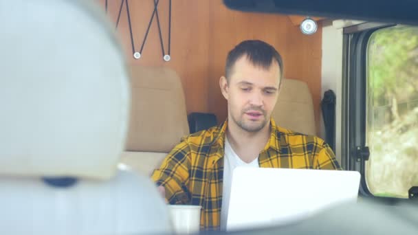 Uomo che usa il suo computer portatile seduto a un tavolo nel camper — Video Stock