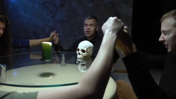 Сеанс спіритизму групи людей, що сидять за круглим столом, тримаючи руки — стокове відео