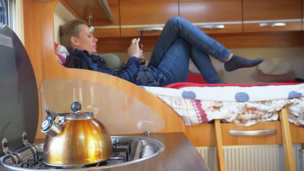 Жінка використовує мобільний телефон, що лежить на ліжку в автономному будинку — стокове відео