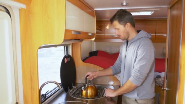 Mann stellt Wasserkocher auf Gasherd im Wohnmobil — Stockvideo