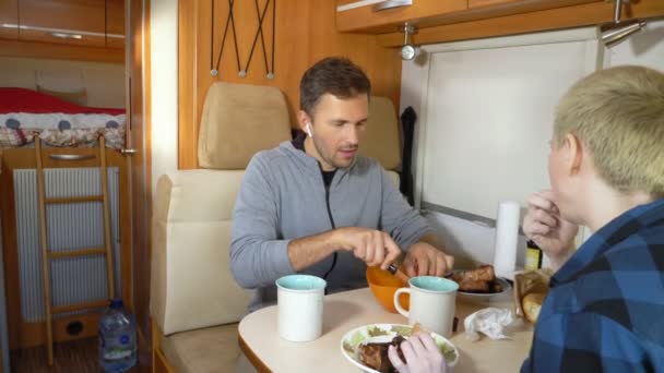 Hombre y mujer comen la carne en la mesa en la autocaravana — Vídeo de stock