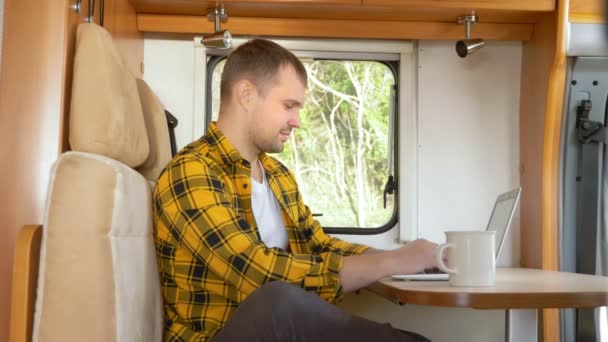 Man met behulp van zijn laptop zitten aan een tafel in de camper — Stockvideo