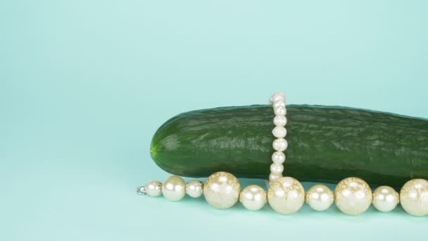 Arte de la moda diseño de alimentos. Pepino fresco con una cadena de perlas. fondo azul — Vídeos de Stock