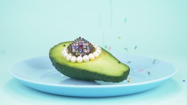 Fashion дизайн еды. половину авокадо с жемчугом, стеклянный шар, конфетти — стоковое видео