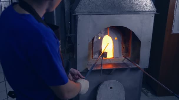 Glassblower. manufacturer of glass products. man heats glass in a furnace — Stock Video