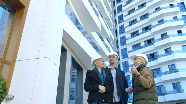 Zwei Frauen und ein Mann mit weißen Helmen. Vortrag über die Hintergründe des Gebäudes — Stockfoto