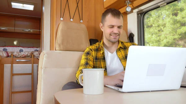 Man met behulp van zijn laptop zitten aan een tafel in de camper — Stockfoto