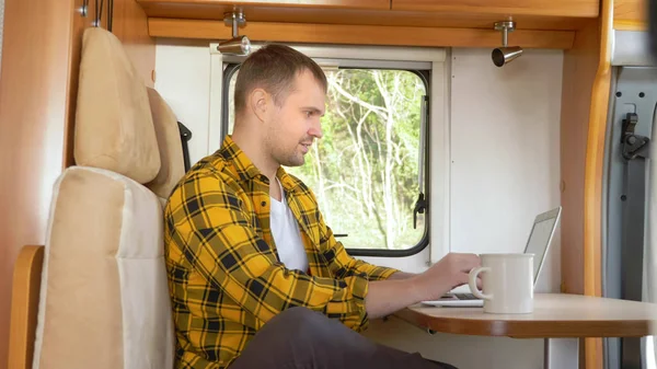 Man met behulp van zijn laptop zitten aan een tafel in de camper — Stockfoto