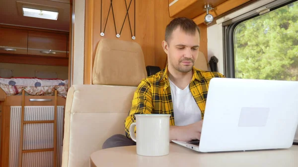 Man met behulp van zijn laptop zitten aan een tafel in de camper — Stockfoto