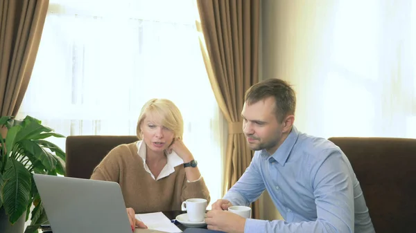 Чоловік і жінка говорять, сидячи в офісі перед ноутбуком — стокове фото