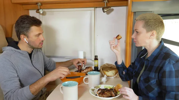 Homem e mulher comem a carne à mesa no motorhome — Fotografia de Stock