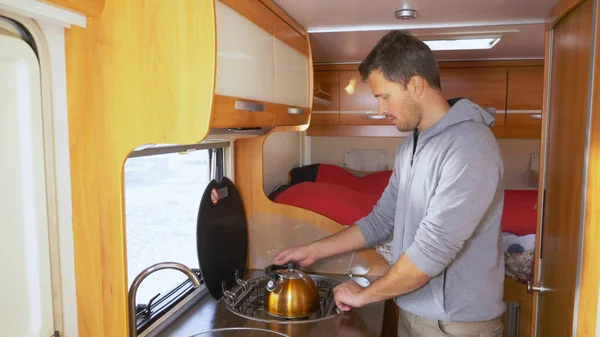 A man washes dishes in a motorhome. car travel concept
