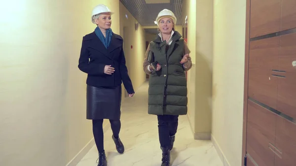 Zwei Frauen in weißen Helmen sprechen drinnen mit grobem Schnitt — Stockfoto