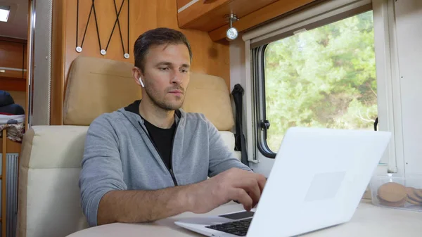 Homme utilisant son ordinateur portable assis à une table dans le camping-car — Photo