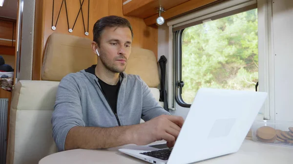 Homme utilisant son ordinateur portable assis à une table dans le camping-car — Photo