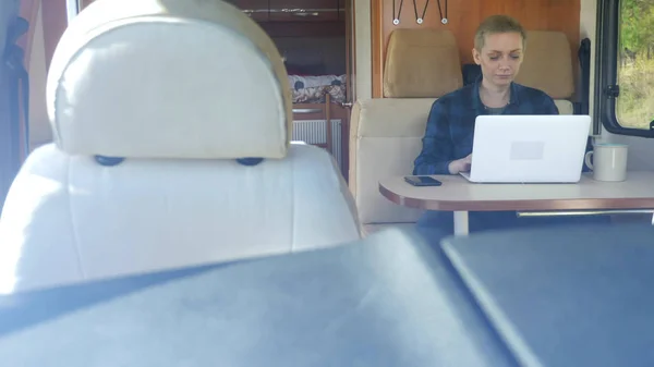 Une femme utilise un ordinateur portable alors qu'elle est assise à une table dans un camping-car . — Photo