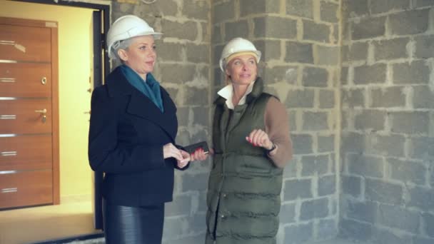 Deux femmes dans des casques blancs parlant à l'intérieur avec des garnitures rugueuses — Video