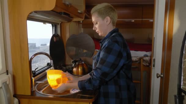 Una mujer lava platos en una autocaravana. concepto de viaje en coche — Vídeo de stock