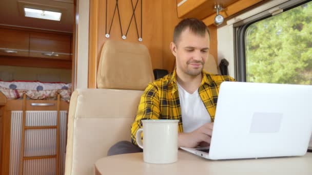 Muž pomocí svého notebooku sedí u stolu v obytném přívěsu — Stock video