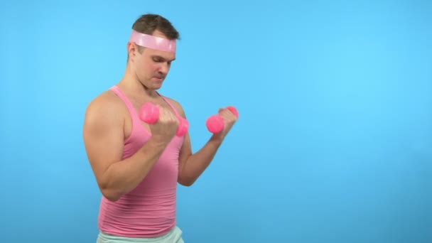 Der verspielte gutaussehende Mann im rosafarbenen Hemd betreibt Fitness mit pinkfarbenen Hanteln. helle Fitness. Sportmodeaccessoires — Stockvideo