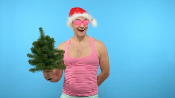 Bel homme ludique dans un T-shirt rose avec des accessoires de Nouvel An élégants à la mode, dans des lunettes roses à la mode, Joyeux Noël et Bonne Année — Video