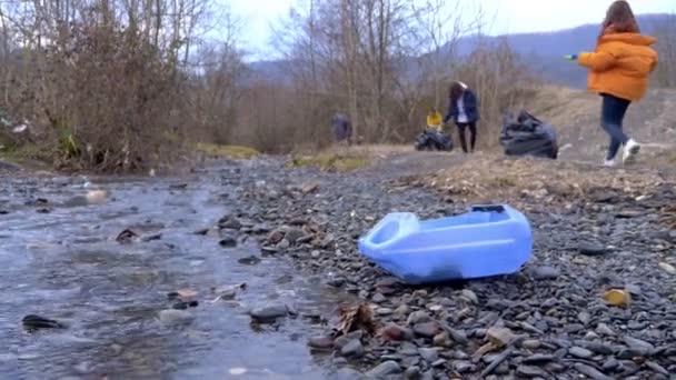 Miljöproblem. frivilliga samlar skräp på stranden av floden — Stockvideo