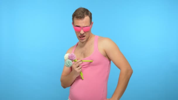 Gutaussehender Mann in pinkfarbener Brille mit Blumenstrauß. blauer Hintergrund — Stockvideo