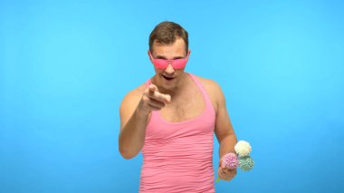 Bir buket çiçekli pembe gözlüklü yakışıklı ucube. mavi arkaplan