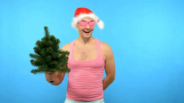 Verspielt gutaussehender Mann in rosa T-Shirt mit modischen stylischen Neujahrs-Accessoires, in modischer pinkfarbener Brille, frohe Weihnachten und ein gutes neues Jahr — Stockfoto