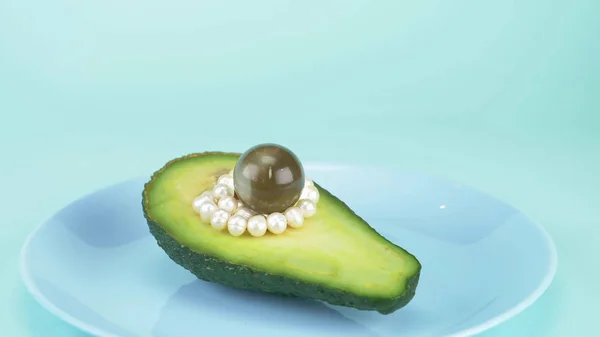 Fashion дизайн еды. половину авокадо с жемчугом, стеклянный шар — стоковое фото
