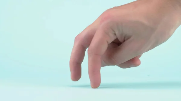 Male hand closeup on blue background. two fingers walk along the surface — Stock Photo, Image