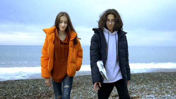 Adolescentes tiran basura de plástico en la playa en el otoño . — Foto de Stock