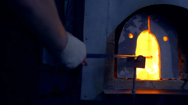Стеклодув. производитель стеклянной продукции. Человек нагревает стекло в печи — стоковое фото