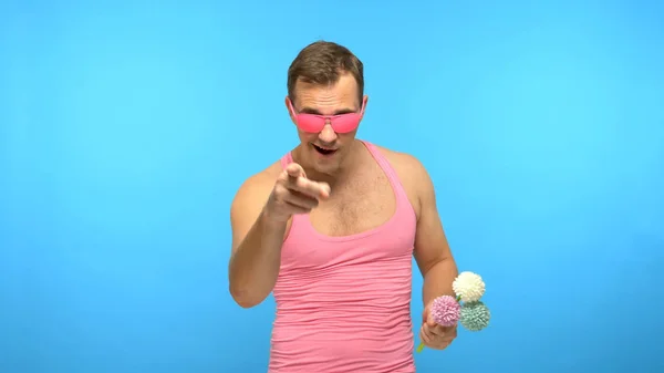Homem bonito aberração em óculos rosa com um buquê de flores. fundo azul — Fotografia de Stock