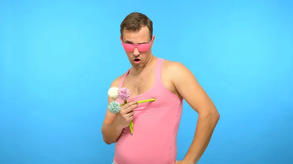 Homem bonito aberração em óculos rosa com um buquê de flores. fundo azul — Fotografia de Stock