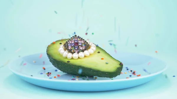 Comida de diseño de moda. medio aguacate con perlas, bola de vidrio, confeti — Foto de Stock