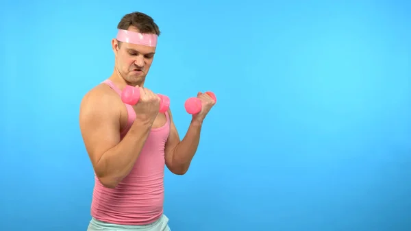 Playful handsome man in a pink shirt is engaged in fitness with pink dumbbells. Bright Fitness. Sports Fashion Accessories — Stock Photo, Image