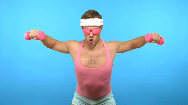 L'uomo bello giocoso in una camicia rosa è impegnato in idoneità con manubri rosa. Bright Fitness. Accessori moda sportiva — Foto Stock