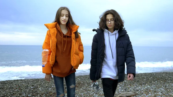 Adolescentes tiran basura de plástico en la playa en el otoño . — Foto de Stock