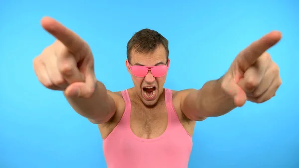 Tipo con estilo en las gafas de color rosa bailando sobre un fondo azul — Foto de Stock